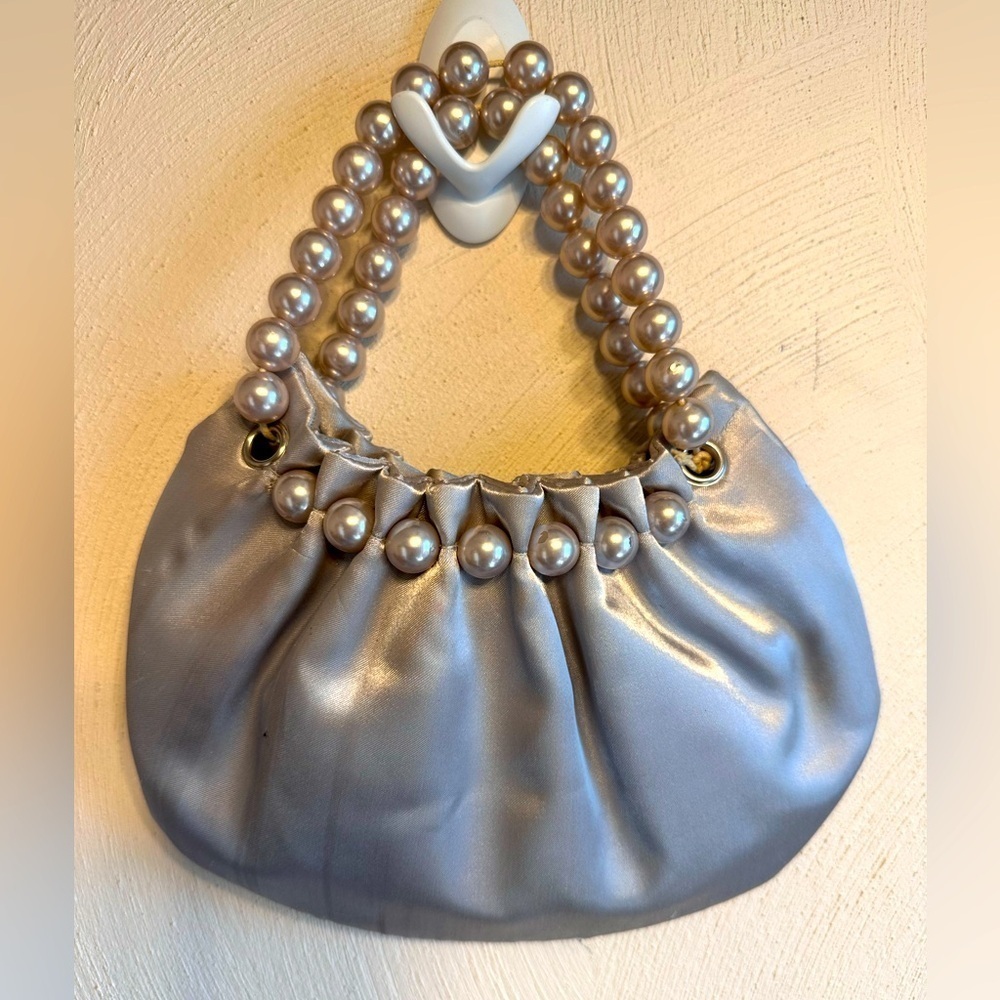 Small satin evening clutch bag with faux pearl handles.